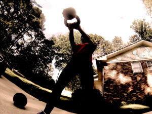 A an image of a female athlete swinging a kettlebell from a ground view. 