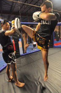 Thai fighter delivering a knee strike displaying functional fitness