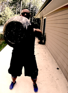 Man performing a kettlebell swing and the image has captured the end of the kettlebell at the peak of the swing at the lifter's chest height. 