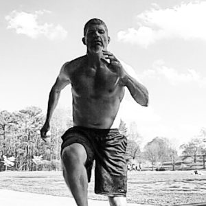 Black and white image of Brandon performing a sprint facing the camera. 