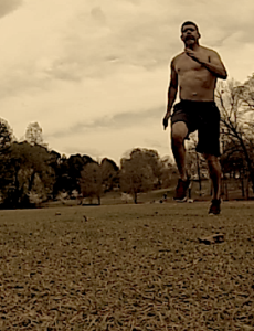 Brandon sprinting on a field at an angle towards the picture. 