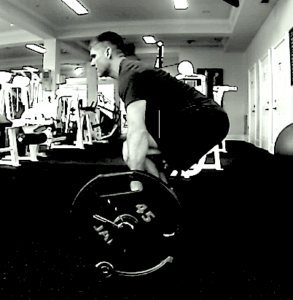 Black and white side view image of Brandon performing the barbell deadlift. 