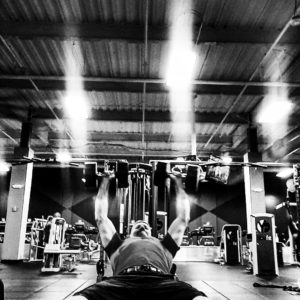 Black and white image of a man dumbbell bench pressing. 