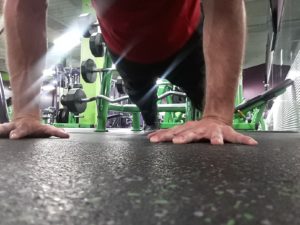 Man doing push-ups with a ground view from the camera angle. 