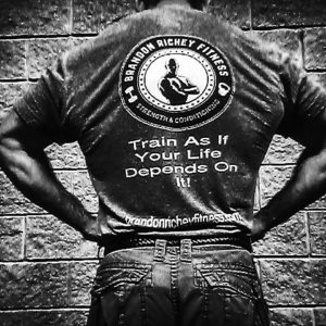 Black and white image with Brandon's back to the camera showing off a lat pose with his T-shirt featuring the BRF ghostman logo. 