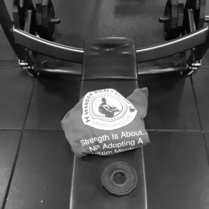 A black and white image of a bench press with the Brandon Richey Fitness hoodie folded at the center of the bench. 