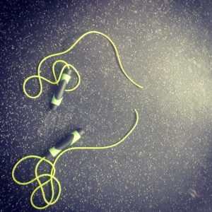 A worn jump rope on the gym floor that has torn in half. 