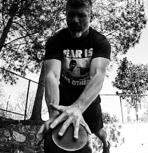 Black and white image of a man doing a crossover push-up over a kettlebell lying with the handle down. 