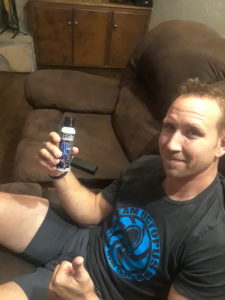 Jeff sitting in a recliner smiling holding a bottle of CobraZol. 